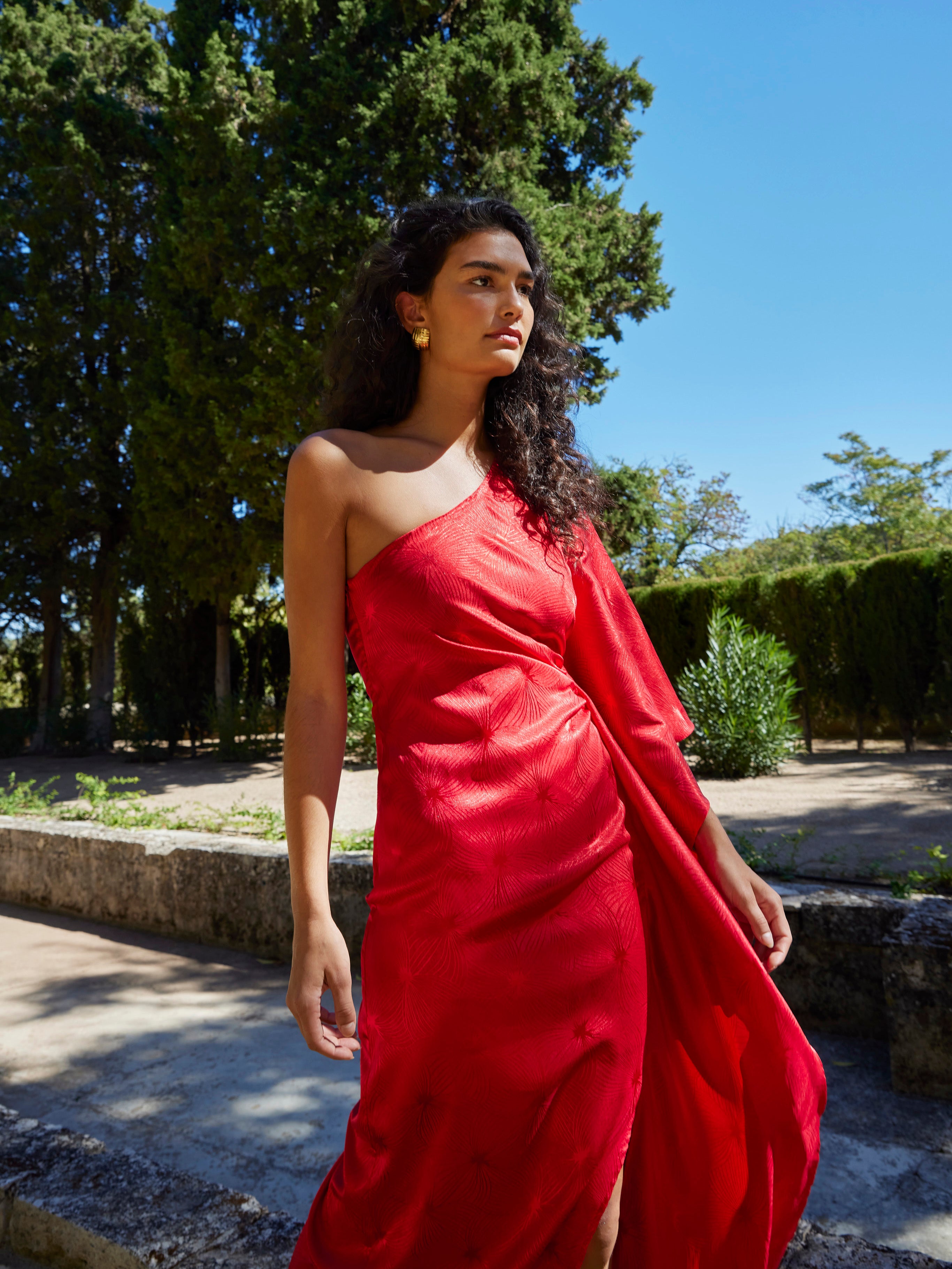 mioh | SANREMO RED - Vestido asimétrico manga capa JCQRD rojo para invitada de boda, fiesta y evento. Tendencia vestidos invitada Primavera Verano 2024. MIOH la marca española de vestidos más de moda